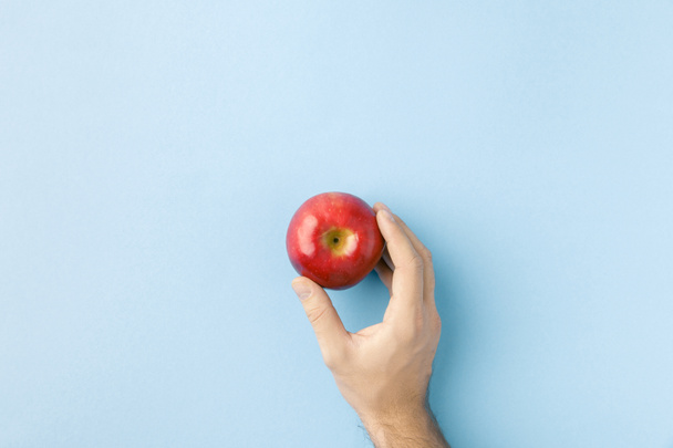 top view of hand holding apple isolated on blue - Photo, Image