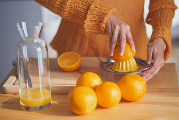 Woman squeezing orange making fresh juice  - Fotó, kép