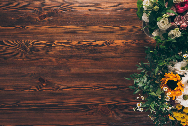 вид зверху на різні квіти на коричневому дерев'яному столі
 - Фото, зображення