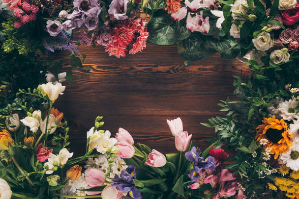 top view of frame of colored flowers on wooden table - Photo, Image