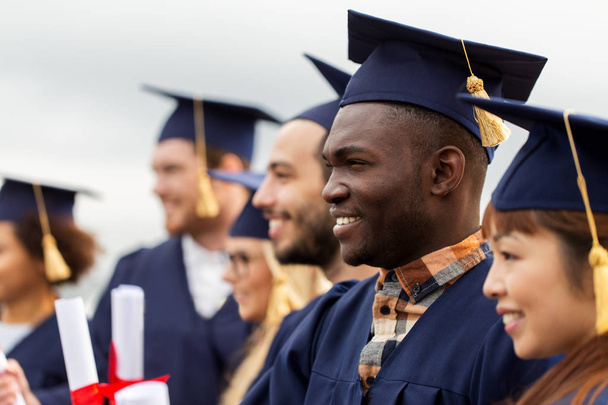 estudantes felizes em placas de argamassa com diplomas - Foto, Imagem
