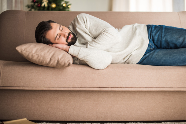 handsome man in sweater sleeping on sofa - Foto, Imagen