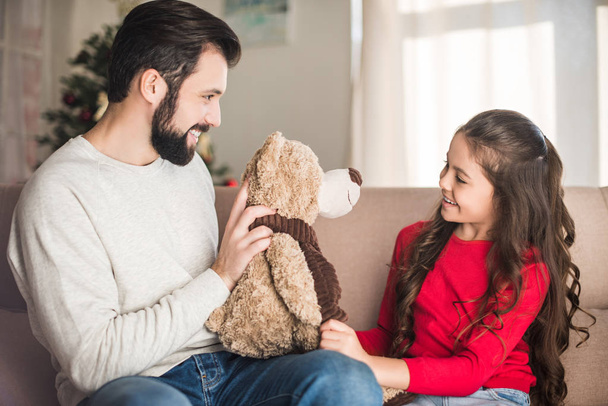 father showing daughter teddy bear  - Foto, Imagen