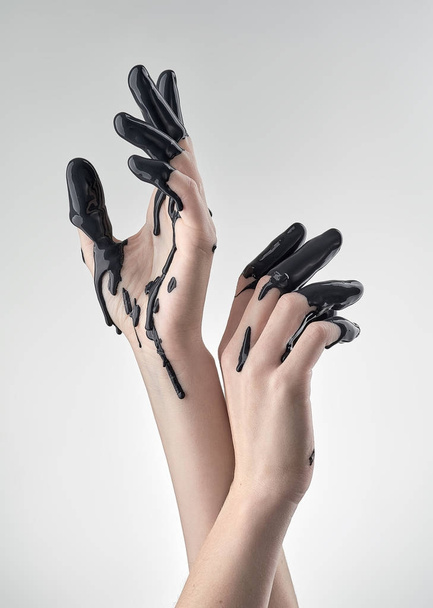 female hand in black oil - Foto, imagen