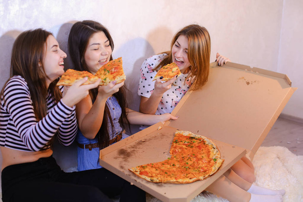 Chicas lindas fresco pasar tiempo y disfrutar de la pizza, sentarse en el suelo en bergantín
 - Foto, imagen