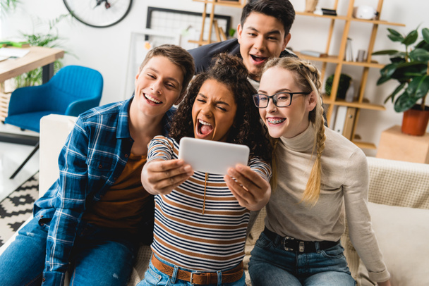 happy multiethnic teenagers taking selfie with smartphone at home - Photo, Image