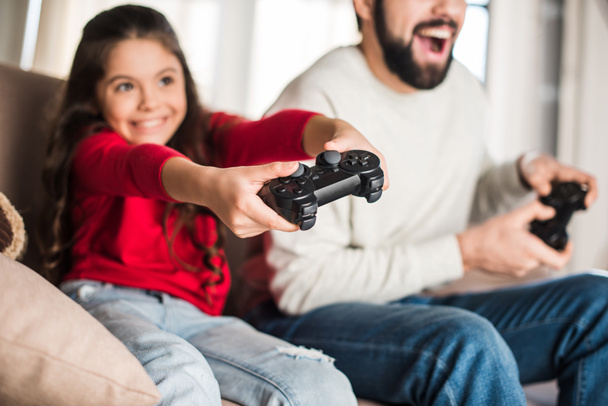 cropped image of father and daughter playing video game with game pads - Фото, зображення