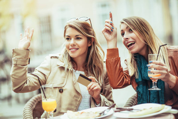 retrato de duas jovens mulheres em restaurante pagando conta com cartão de crédito
 - Foto, Imagem