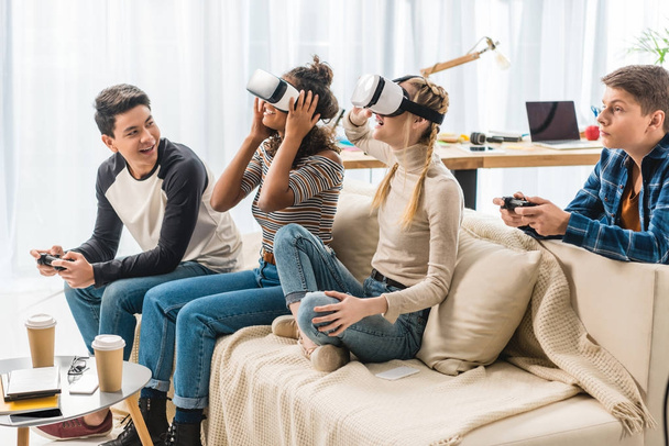 aufgeregte multikulturelle Teenager-Mädchen, die etwas mit Virtual-Reality-Headsets ansehen  - Foto, Bild