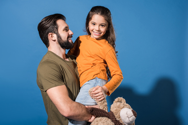 handsome father holding daughter on blue - Foto, Imagen