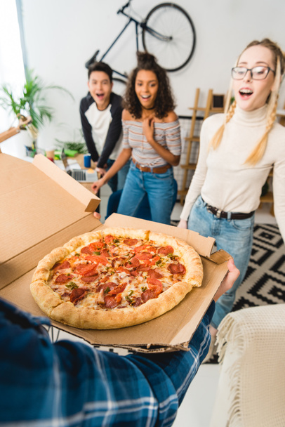 excited multicultural teens looking at pizza - Fotó, kép