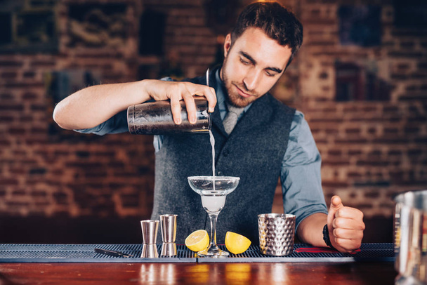 Close up of barman hands adding ice and tequila to modern urban cocktails. Sky bar serving elegant drinks - 写真・画像
