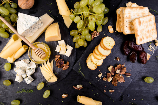 Cheese plate. Assortment of cheese with walnuts, bread an honey on stone slate plate. - Valokuva, kuva