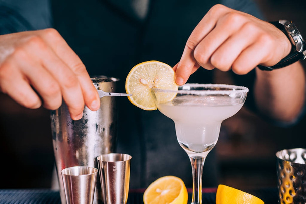 Close up of barman hands preparing margarita cocktail in fancy glass at nightclub - Foto, afbeelding