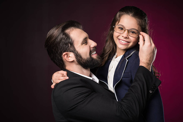 father fixing daughter glasses on burgundy - Photo, Image
