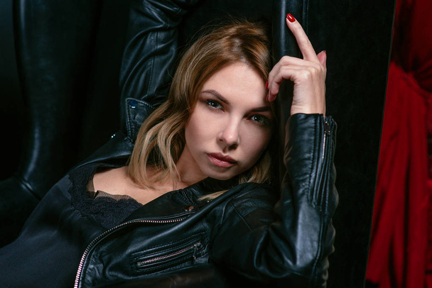 Retrato de la joven atractiva mujer rubia con estilo en vestido de seda y chaqueta negra en el sillón
 - Foto, imagen