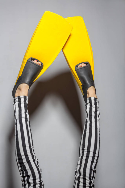 Woman wearing yellow flippers over gray background - Foto, immagini