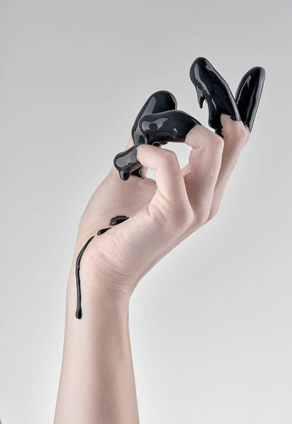 female hand in black oil - Фото, зображення
