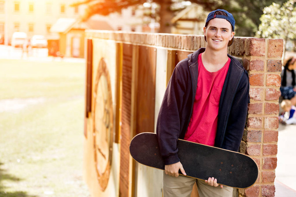 Teenage boy with skateboard standing outdoors - Foto, immagini