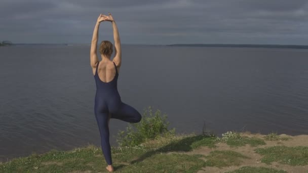Yoga vrouw in sportkleding vormen tegen lake - Video