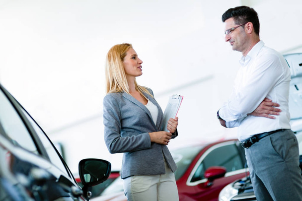  salesperson selling cars at dealership to buyer - 写真・画像