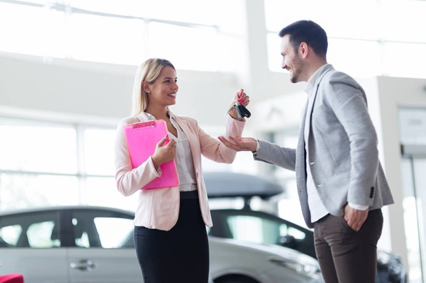 salesperson selling cars at dealership to buyer - Foto, imagen