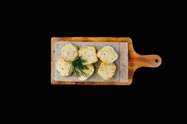 Bread with cheese. Fried garlic croutons with dill. On a wooden board. Top view. Isolated on a black background - Photo, Image