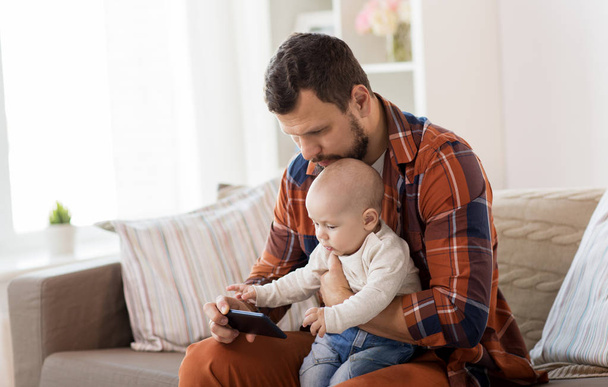 father and baby boy with smartphone at home - Foto, Bild