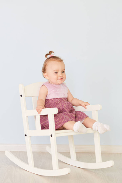 hermosa niña en un vestido se sienta en una silla blanca
 - Foto, imagen