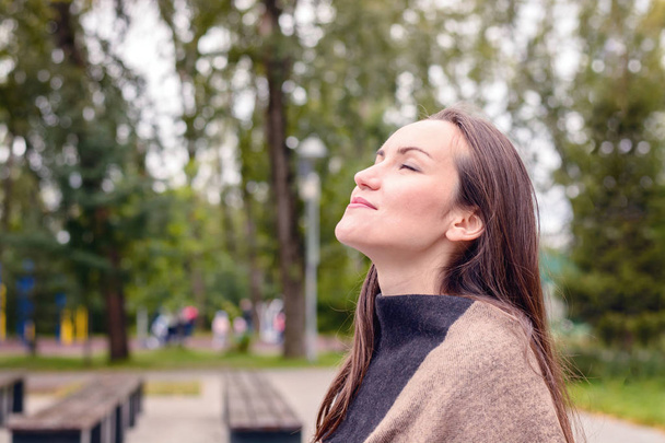 Портрет молодой красивой женщины, дышащей свежим осенним воздухом в зеленом парке. концепция чистого атмосферного воздуха, окружающей среды
 - Фото, изображение