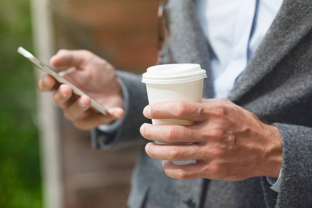 businessman hand holding morning coffee and reading phone - Zdjęcie, obraz