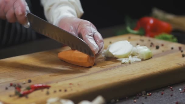 De chef-kok snijdt wortel. wortel als ingrediënt voor het maken van soep of een andere schotel. Bovenaanzicht Slow motion - Video
