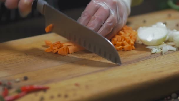 De chef-kok snijdt wortel. wortel als ingrediënt voor het maken van soep of een andere schotel. Bovenaanzicht Slow motion - Video