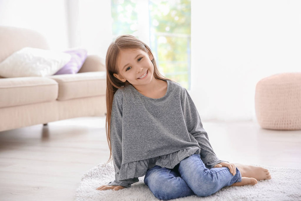 Χαριτωμένο μικρό κορίτσι που κάθεται στο πάτωμα στο σπίτι - Φωτογραφία, εικόνα