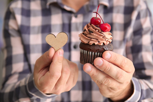 Man holding tasty cupcake and wooden heart for Valentine's Day - Φωτογραφία, εικόνα
