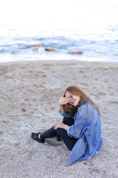 Beautiful girl resting, sitting by sea and posing on camera on b - Photo, Image