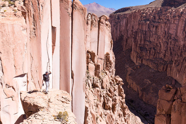 Tourist man adventurer backpacker standing above deep canyon, Bolivia - Photo, Image