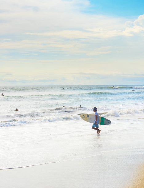 CANGGU, BALI ISLAND, INDONESIA - JAN 19, 2017: Surfer going to surf in the ocean. Bali island is one of the worlds best surfing destinations - 写真・画像