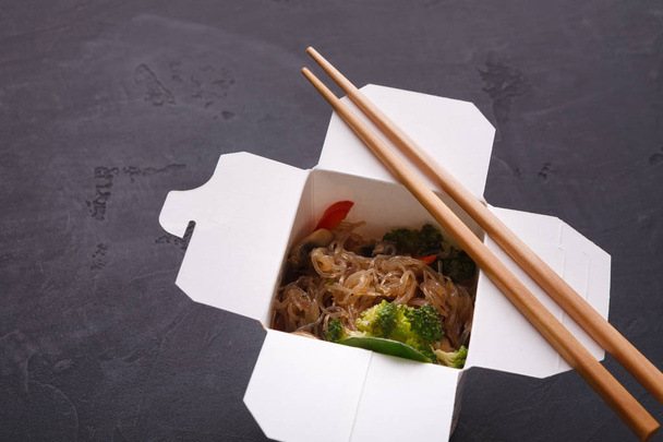 Aziatisch eten in levering vak op grijze achtergrond - Foto, afbeelding