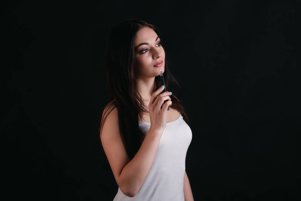 Young woman vaping e-cigarette on black - Fotografie, Obrázek