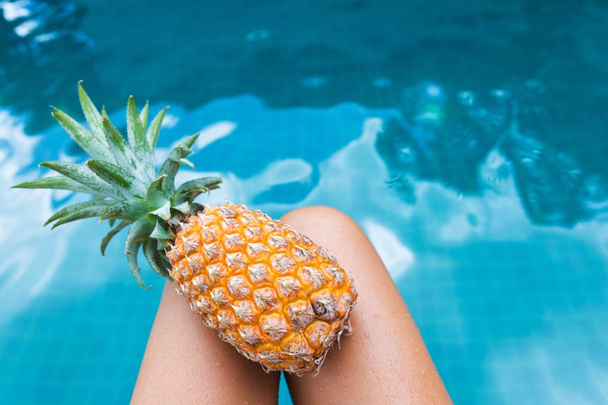 Fresh yellow pineapple tropic fruit summer woman carrying near pool - Фото, изображение