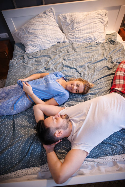 romantyczna miłość szczęśliwa para leżąc na łóżku z organami w przeciwnych kierunkach podczas patrzenia na siebie - Zdjęcie, obraz