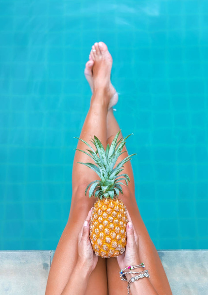 Slim woman holding pineapple fruit near swimming pool tropical exotic concept - Foto, imagen