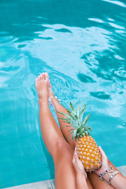 Slim woman holding pineapple fruit near swimming pool tropical exotic concept - Photo, image