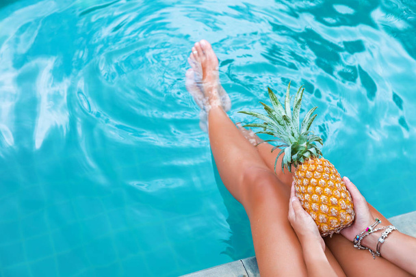 Slim woman holding pineapple fruit near swimming pool tropical exotic concept - Foto, imagen