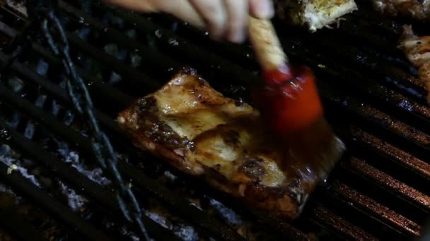 Gerookte ribben zijn bedekt met tomatenketchup op een BBQ-grill - Video