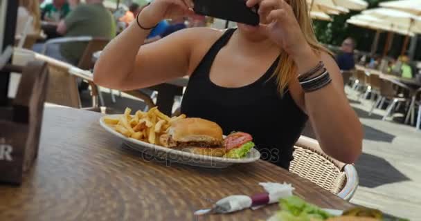 Mujer joven en el sombrero de béisbol fotos de su comida en el restaurante al aire libre
 - Metraje, vídeo