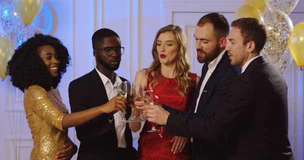 Young multi ethnical people drinking Champagne and doing cheers with glasses at the glamorous party. Friends celebrating something. Indoors - Foto, Bild