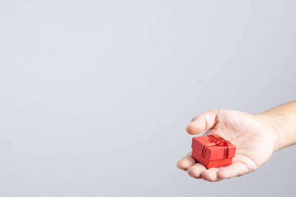 Caja de regalo pequeña de mano roja con cinta y lazo para ocasiones especiales sobre fondo blanco
 - Foto, imagen