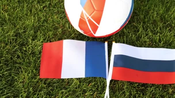 Μπάλα ποδοσφαίρου και σημαίες της Ρωσίας και της Γαλλίας. Ποδόσφαιρο, μπάλα στο γρασίδι. - Πλάνα, βίντεο